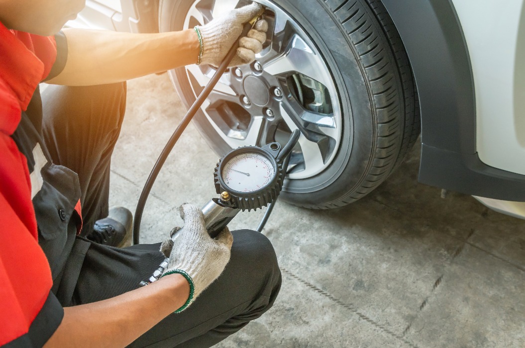 Close up mechanic inflating tire and checking air pressure with gauge pressure in service station