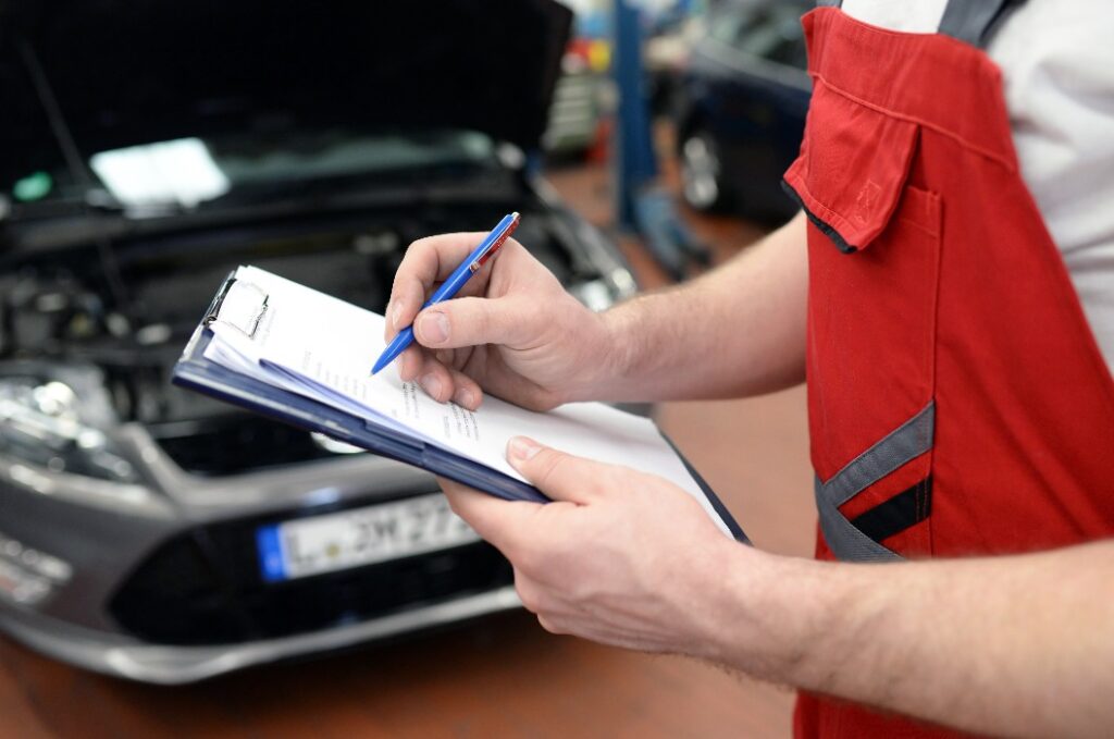 KFZ Mechaniker überprüft ein Fahrzeug in der Werkstatt - checkliste Funktion // Car mechanic checks a vehicle in the workshop - checklist Function