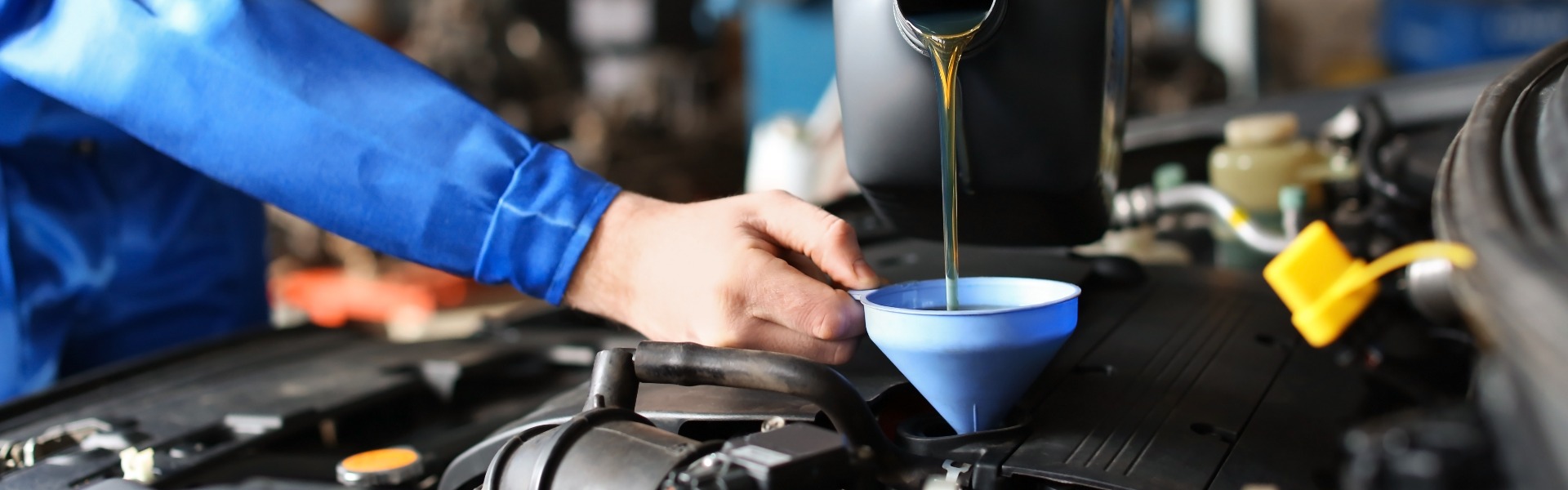 Male mechanic refilling car oil in service center